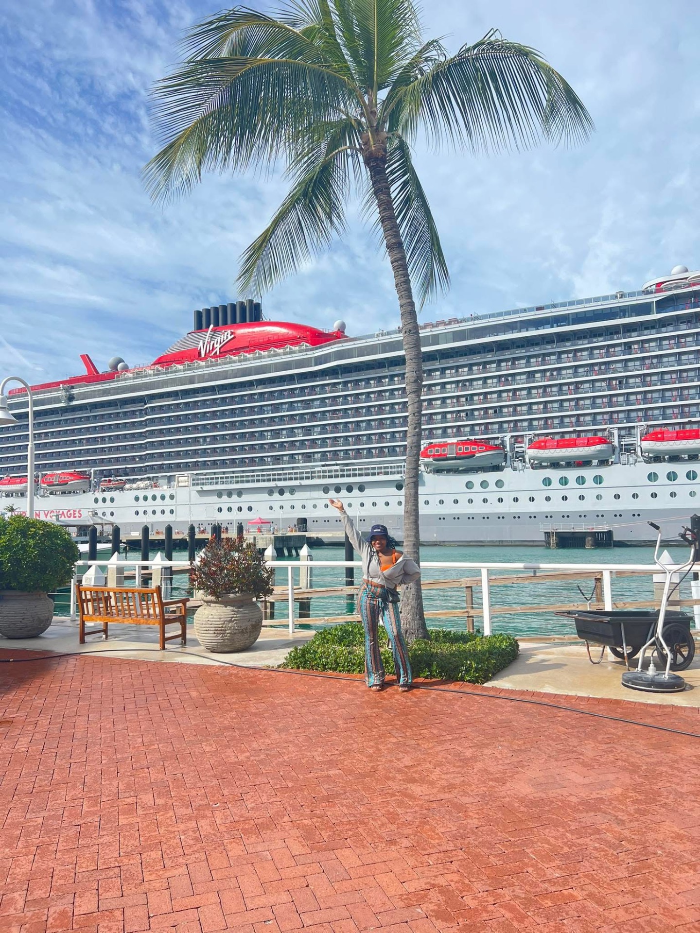 Iesha Gee posing in front of a Virgin Voyages cruise ship at the port